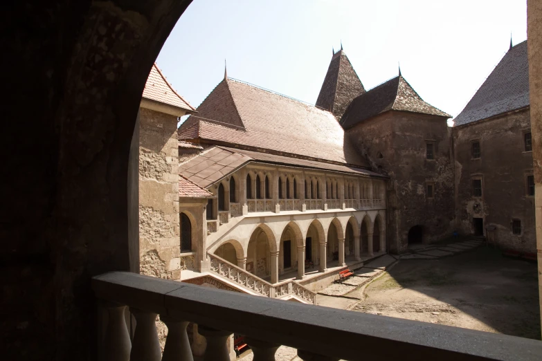 a castle courtyard with pillars and buildings in the distance