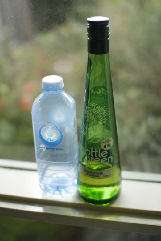 an bottled water and a bottle of soda sitting on a window sill