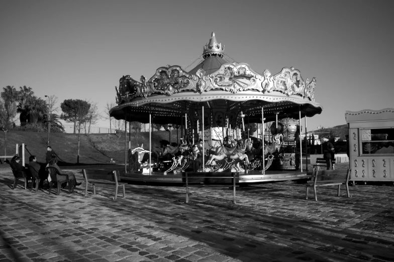 a merry go round in black and white sits on a brick path