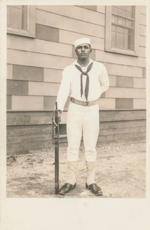 black and white po of man in uniform wearing hat and gloves with a baseball bat