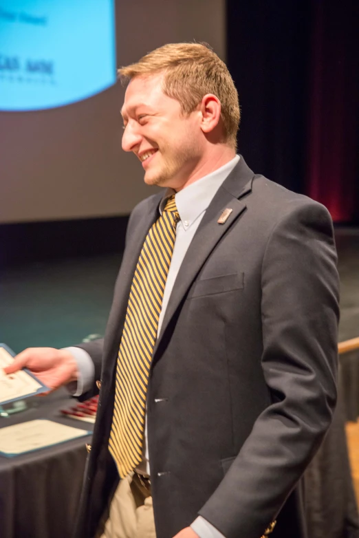 a man smiles while standing in front of an audience