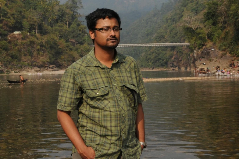 a man is standing by the water with trees on both sides of his face