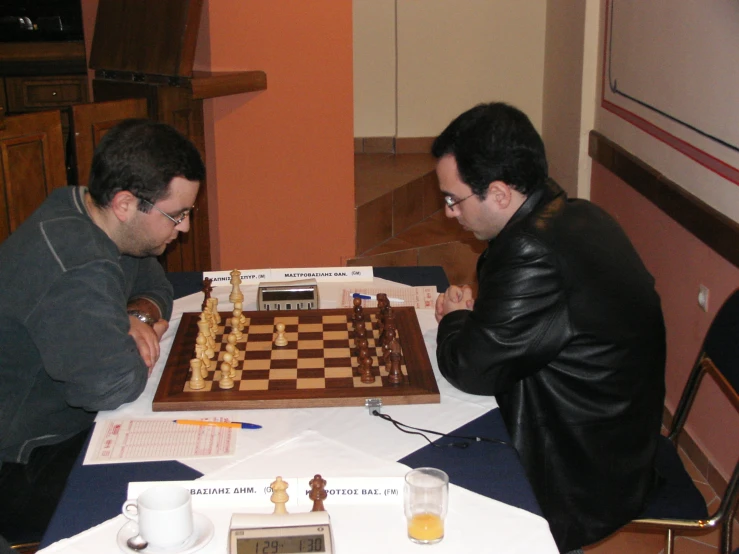 two men sitting at a table in front of chess boards