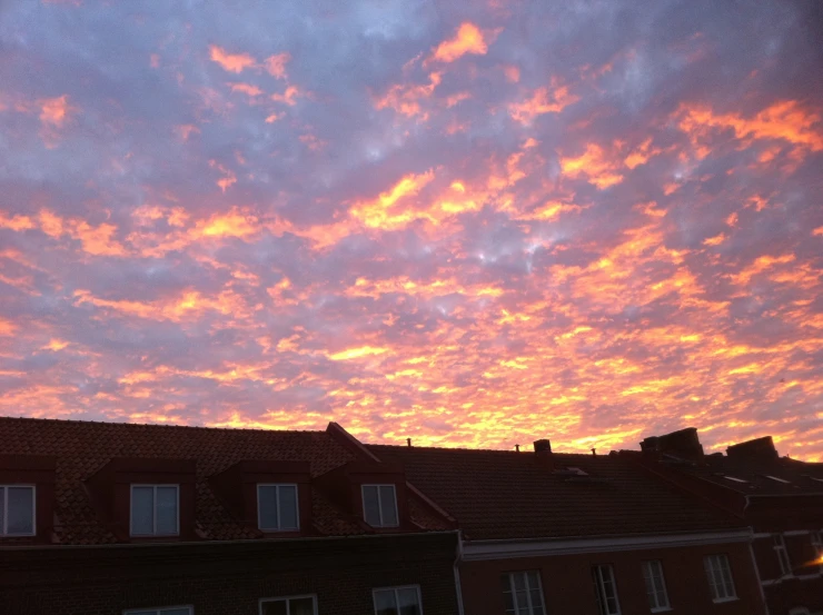 colorful clouds fill the skies on an evening over some buildings