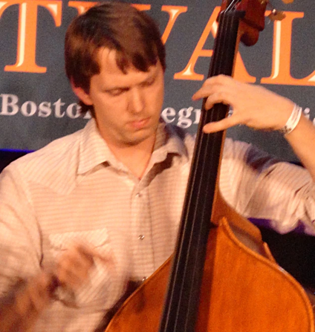 a man with brown hair holding an instrument and playing music