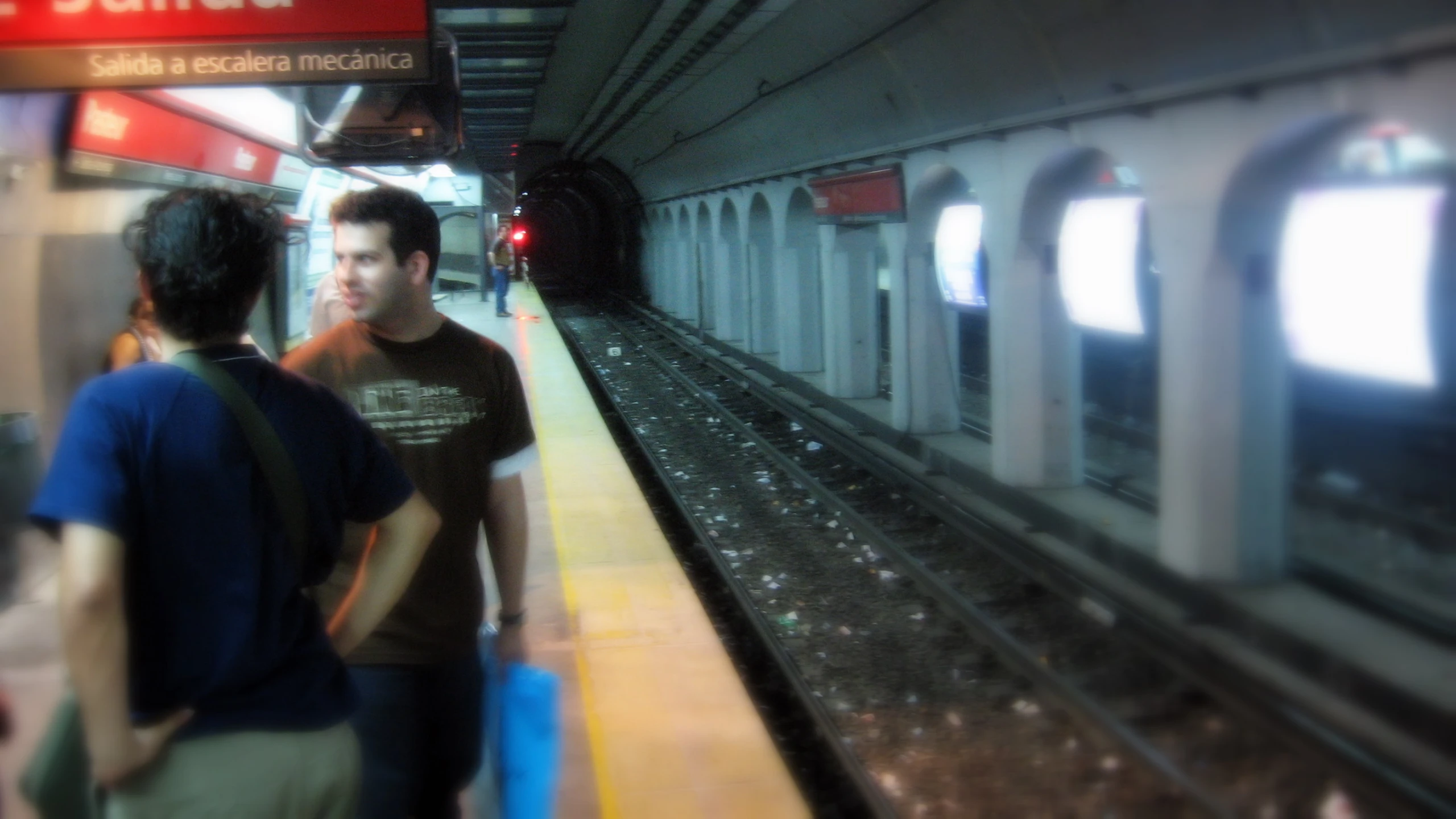 two people walking on the train platform in the rain