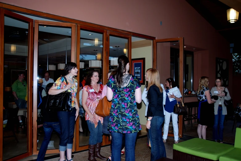 several women standing outside of a building talking to each other