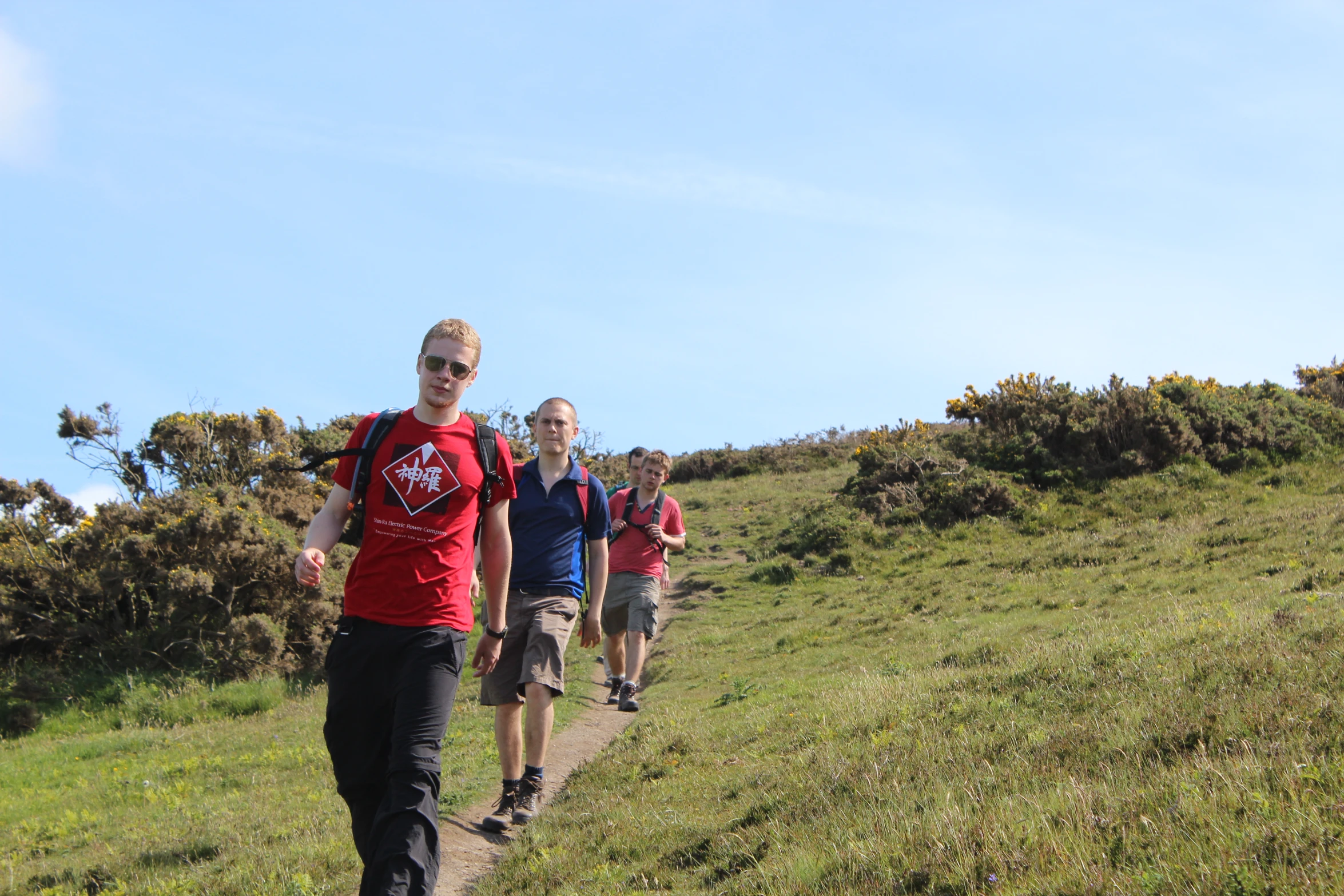 three men walk together along the trail in a grassy area