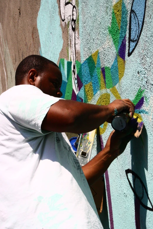 an adult painting a wall with graffiti in the sun