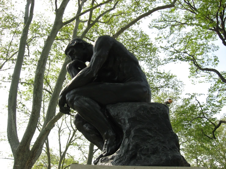 a statue sits on a large rock in a park