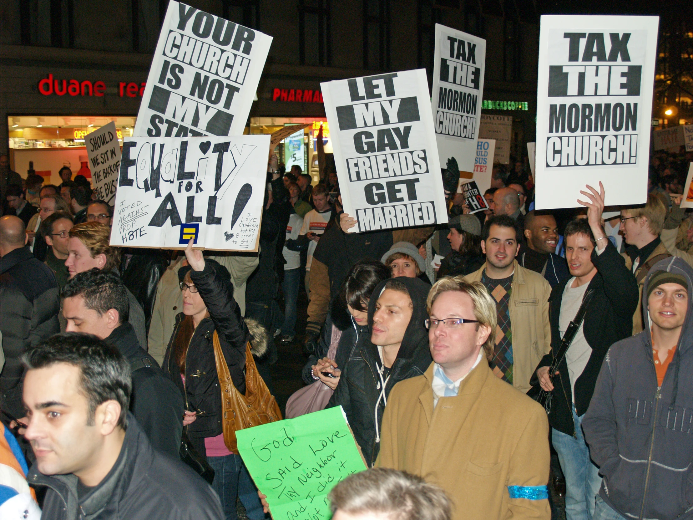 a group of people protesting outside on the sidewalk