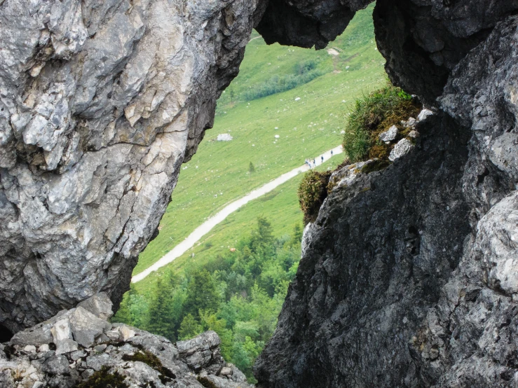 a rock tunnel with sheep and green landscape as seen from below