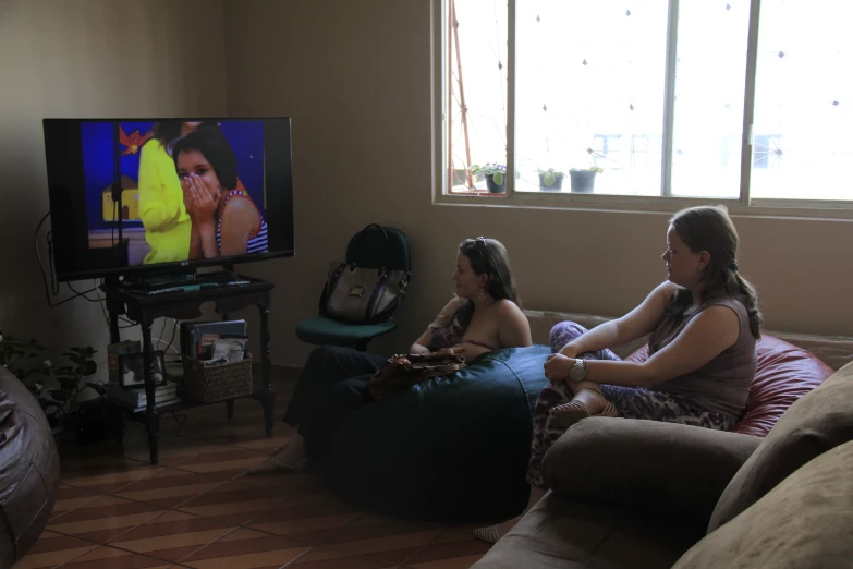 two women sitting in front of the television