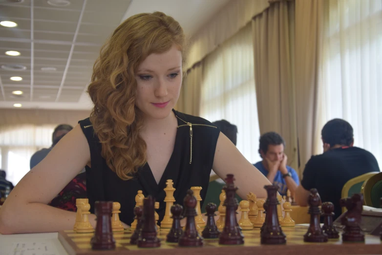 a woman is sitting in front of a chess board and her pawn
