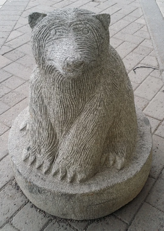 a statue of a bear sitting on top of a cement block