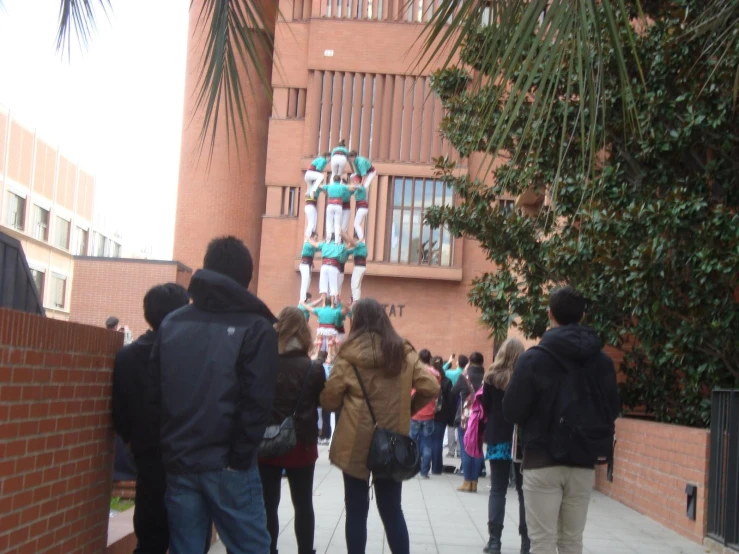 several people are walking down the sidewalk by a building