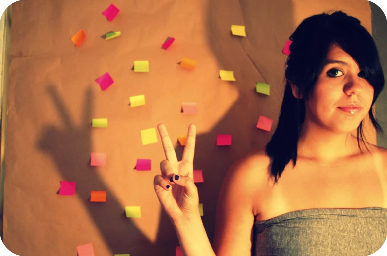 a young woman stands in front of a wall with many post - it notes