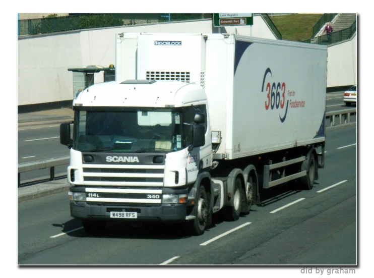 large white truck driving along the road near a building