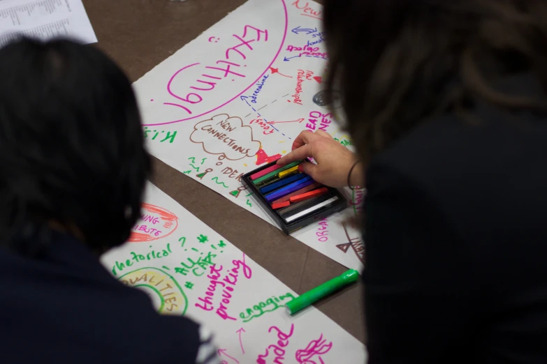 a woman writing on a large piece of paper