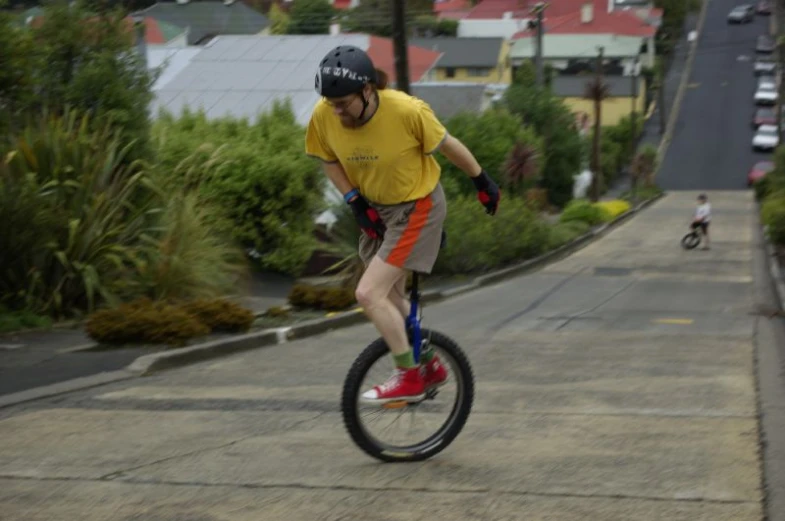 a young man in yellow shirt riding on top of a small bicycle