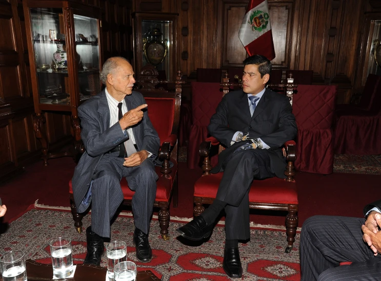 a couple of men in suits and ties sitting on chairs