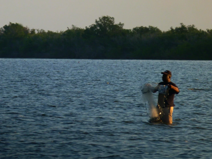 a man is wading across the water with his dog