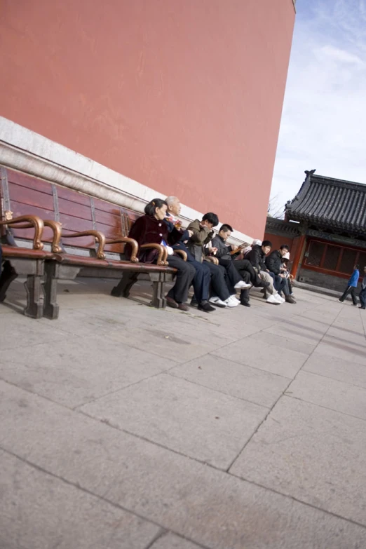 several people sitting outside with benches and buildings in the background