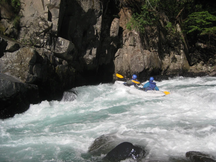 two people paddling kayaks down a raging river