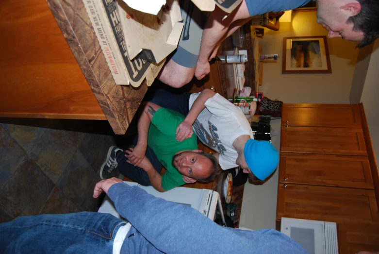 four people standing around a man in a green shirt