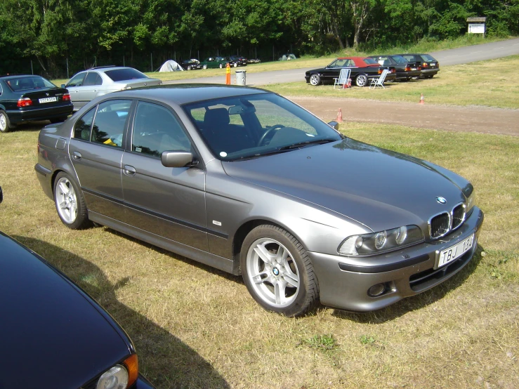 a grey bmw is parked outside in a grassy field