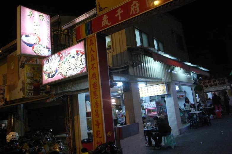 a sidewalk with lots of people and bikes in front of an asian restaurant