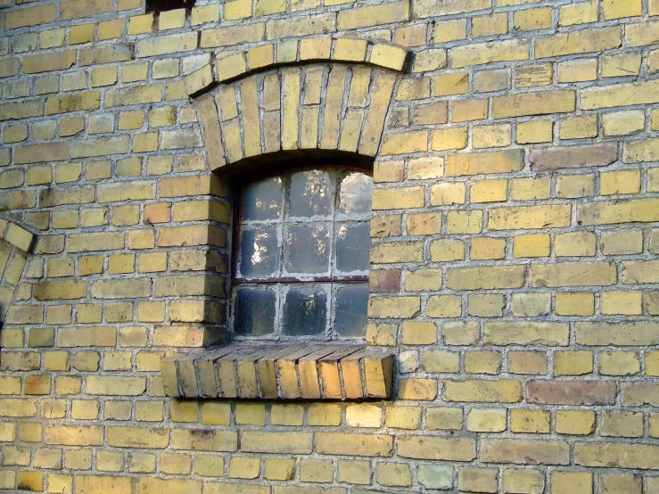 an old window with broken bars on a brick building