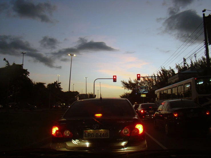 two cars stopped at a stop light in the evening