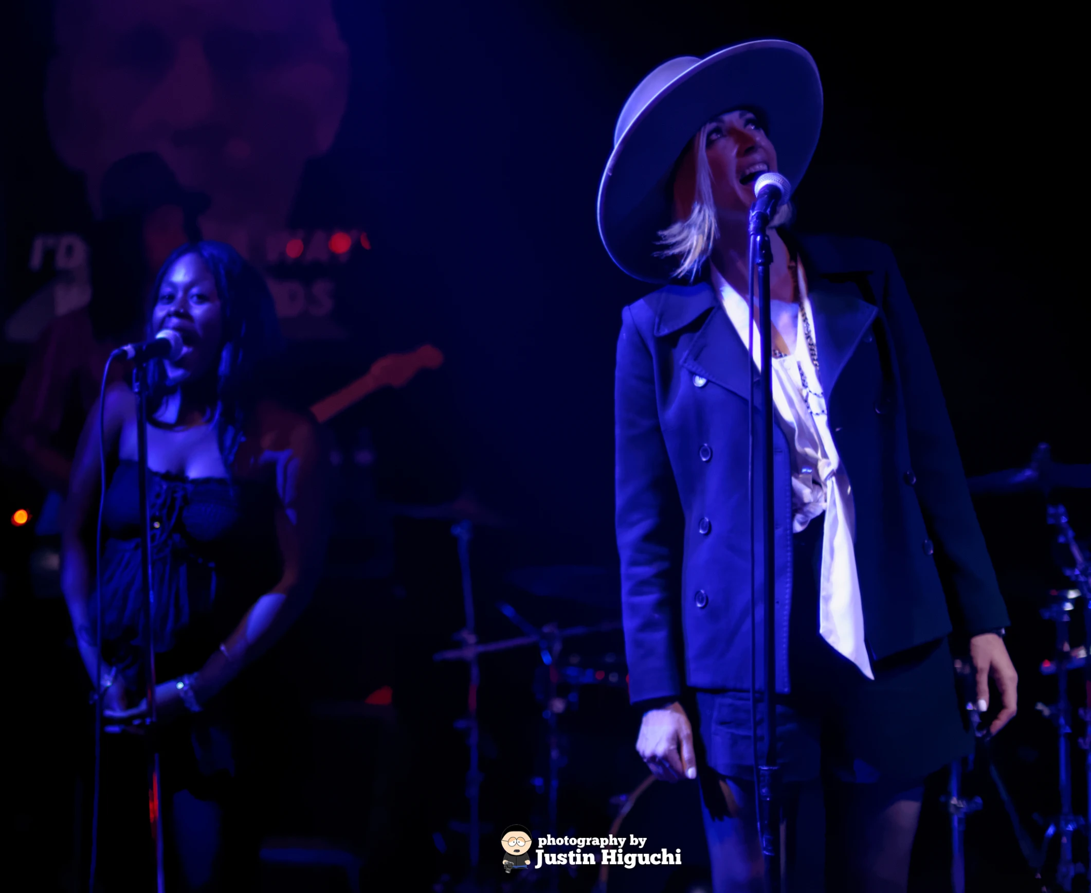 two women on stage with a hat on