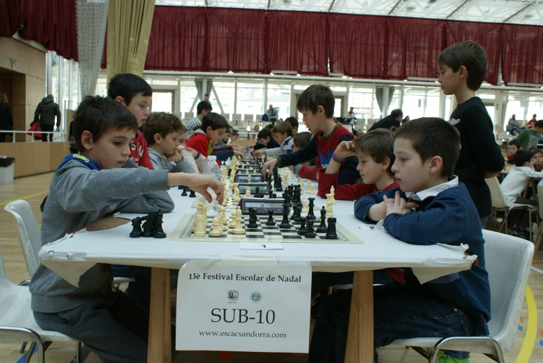 a bunch of boys playing chess at the table