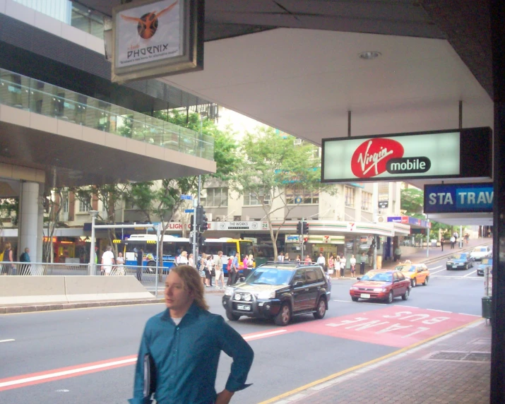 a man is walking past parked cars and a billboard