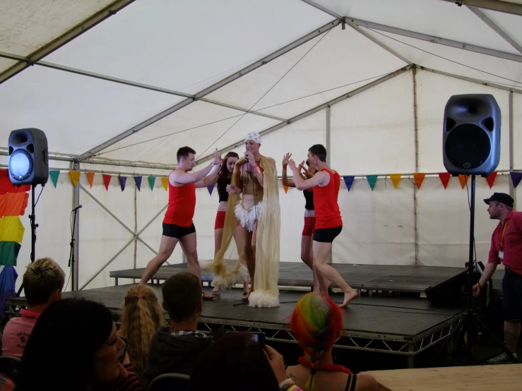 people standing on a stage with speakers and curtains