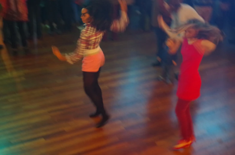 two young people dancing on a wood floor