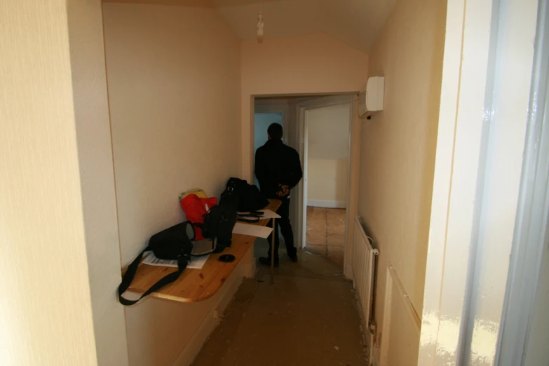 two people walk down a hallway between desks and chairs