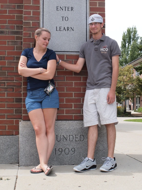 a man and woman pose together near a plaque