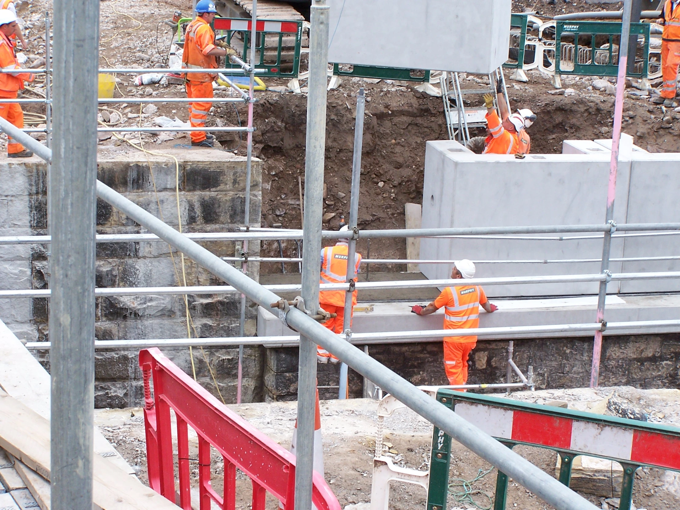 a group of workers in orange shirts standing next to cement