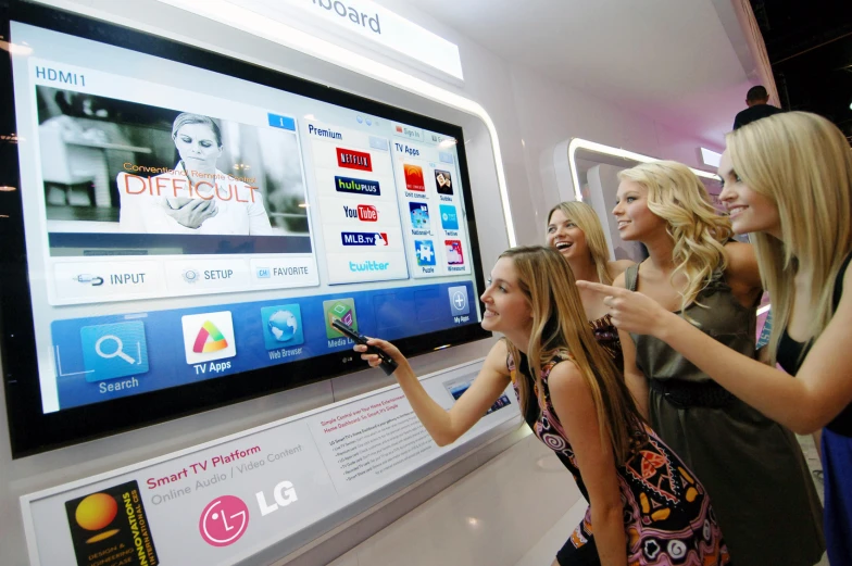 a group of women standing in front of a large television