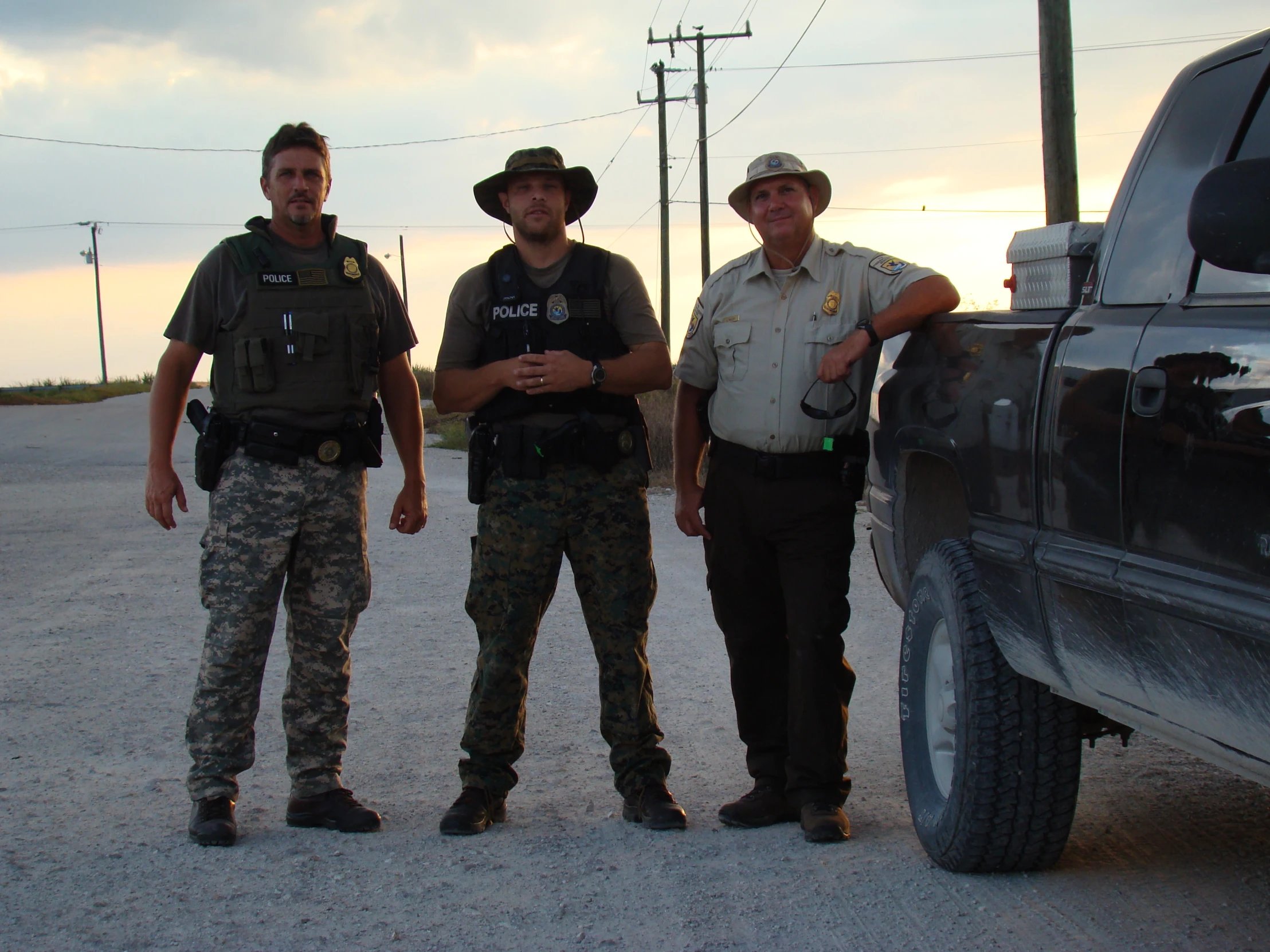 three guys are posing in front of a truck