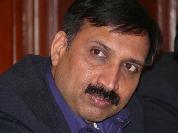 an indian man wearing a purple shirt and dark suit