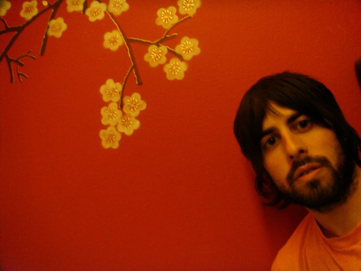 a bearded man with a beard standing next to a wall