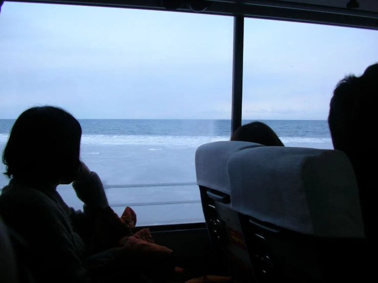 passengers ride a bus down a beach with the ocean in the background