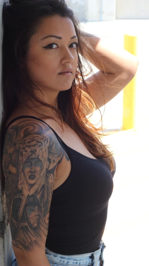 a woman with tattoos standing on her legs and looking down at the camera