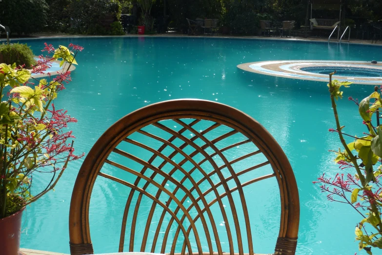 a wicker chair sitting near a pool on the shore