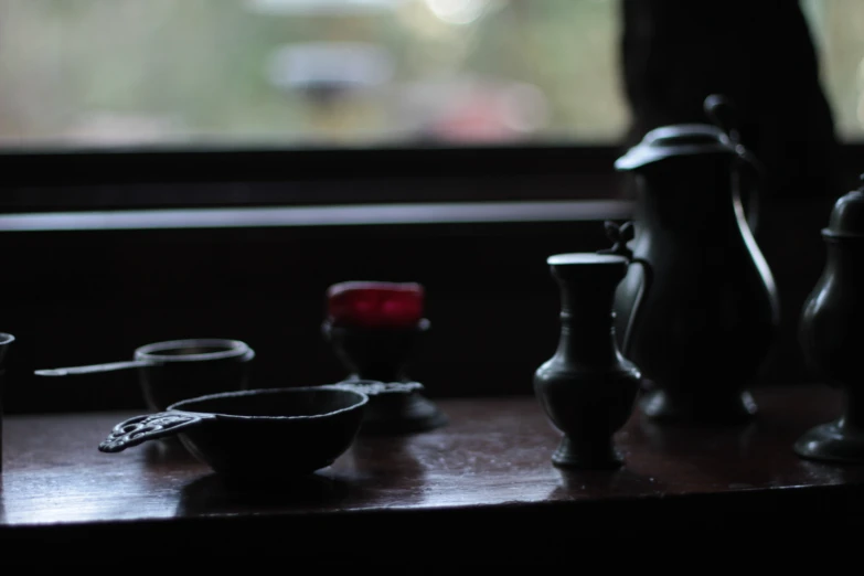 a dark room with some pottery, pots and spoons