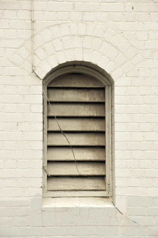 a white brick wall and window with a long thin bars of glass